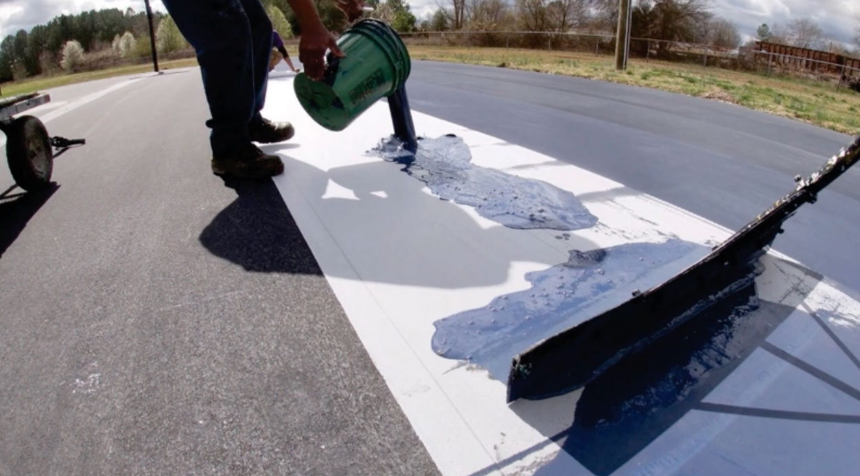 Crew installing Polypave across an asphalt tennis court