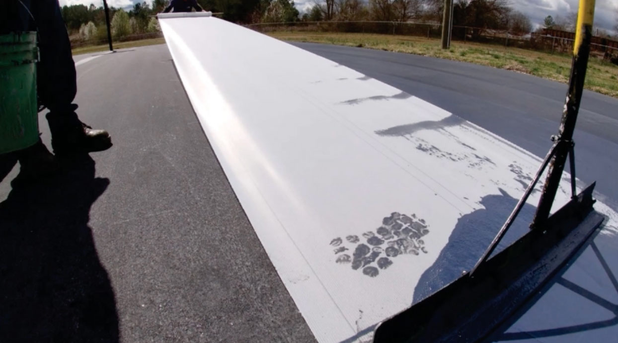 Crew installing Polypave across an asphalt tennis court