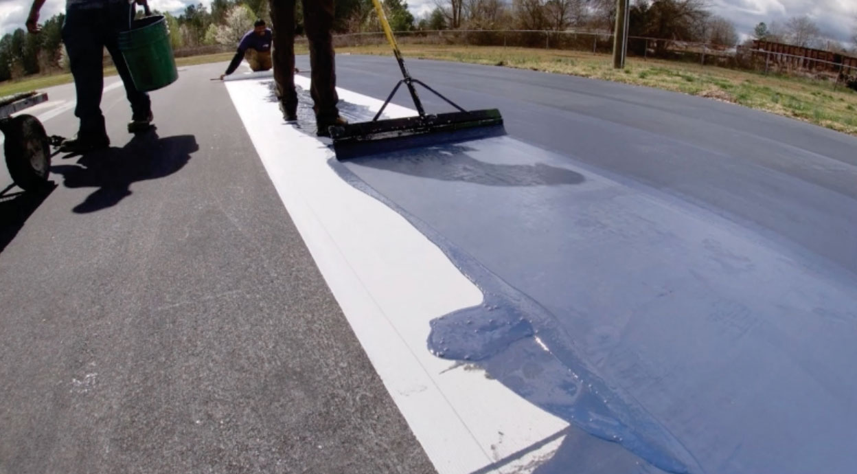 Crew installing Polypave across an asphalt tennis court